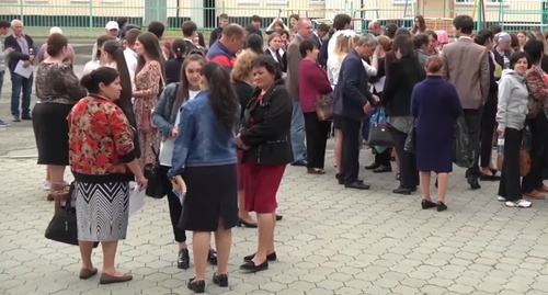 Родственники сдающих экзамен выпускников у одной из школ Карачаево-Черкесии. Скриншот из сюжета телеканала "Архыз 24", YouTube.com Родственники сдающих экзамен выпускников у одной из школ Карачаево-Черкесии. Скриншот из сюжета телеканала "Архыз 24", YouTube.com