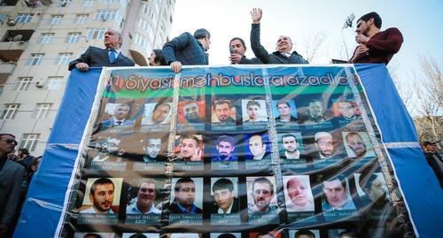 Участник митинга в Баку в апреле 2017 года держит в руках портреты политзаключенных. Фото Азиза Каримова для "Кавказского узла" Участник митинга в Баку в апреле 2017 года держит в руках портреты политзаключенных. Фото Азиза Каримова для "Кавказского узла"