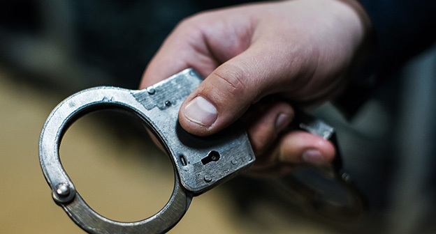 Сотрудник полиции держит наручники. Фото Елены Синеок, Юга.ру