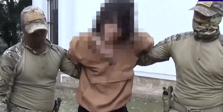 Силовики ведут задержанного в Майкопе. Стоп-кадр видео от 11.07.25, https://t.me/tass_agency/260085
