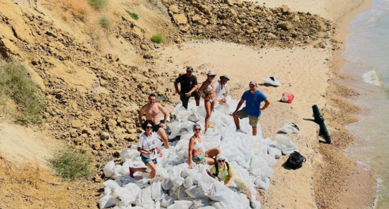 Волонтеры на фоне собранных мешков с загрязненным мазутом грунтом. Фото предоставлено "Кавказскому узлу" штабом "Дельфины"