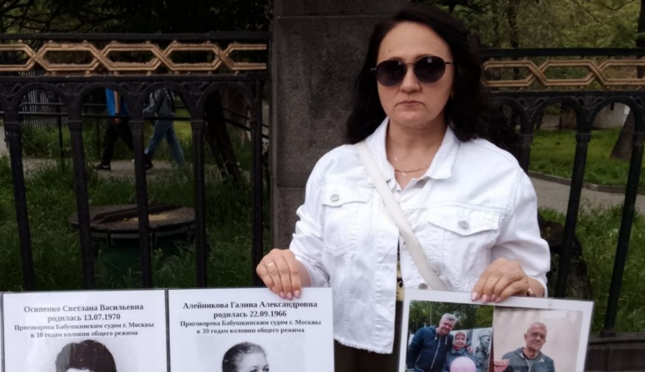 Участница пикета держит в руках плакаты. Скриншот фото RusNews от 02.05.26, https://t.me/rusnews/84132.