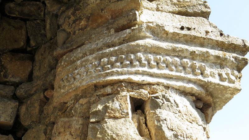 Капитель с архаичными орнаментами в виде зубцов.