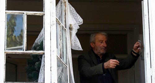 Мужчина снимает остатки стекла с окна после обстрела Мартуни 14 октября 2020 года. Фото: REUTERS/Stringer